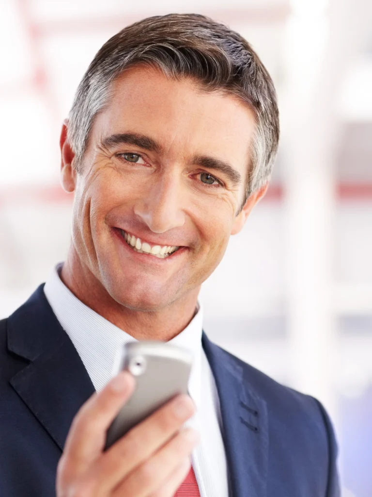A man in suit and tie holding a cell phone.